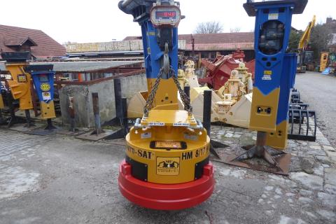 Hydraulik-Abbruch-Magnet ART-1-013 – hängend an Kranwaage zur Gewichtskontrolle, im Hintergrund weitere Hydraulikhämmer (Herstellerkontext)