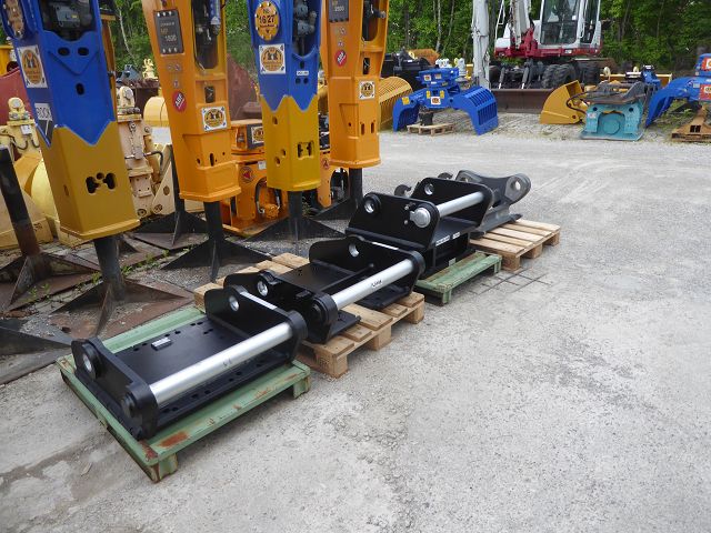Weitwinkelaufnahme Lagerhof – Reihe von 3 Adapterplatten (u. a. die angebotene SW-66-Platte) vor orangen/blauen Hydraulikhämmern