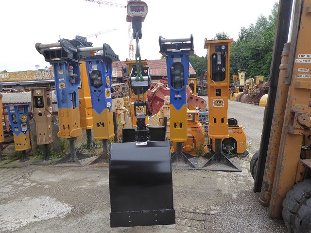 2-Schalen-Hydraulik-Greifer ART-274-005 – hängend an Kranwaage, Baukran im Hintergrund, Digitalanzeige nicht scharf lesbar
