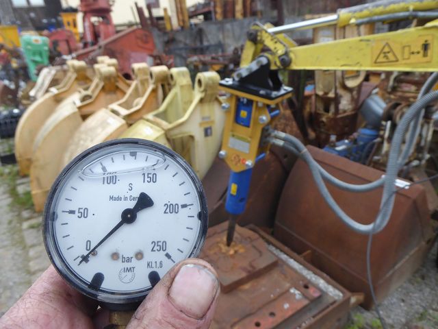 Hydraulikhammer ART-45-003 – im aktiven Einsatz beim Hämmern auf Schrottteil, Druckanzeige im Vordergrund
