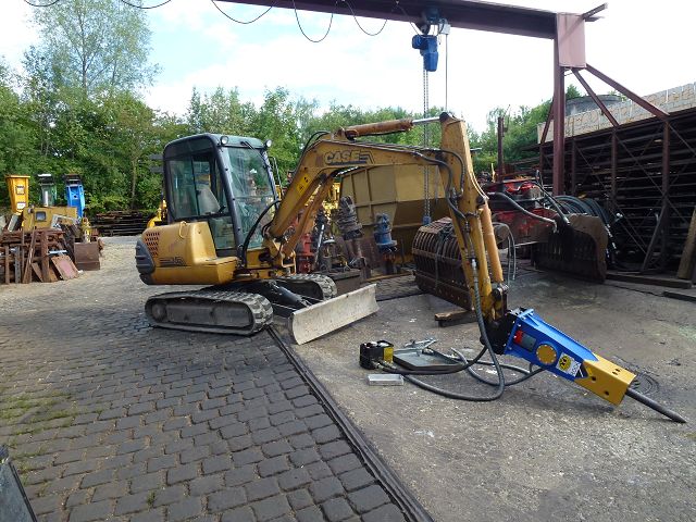 Hydraulikhammer ART-45-007 – CASE-Minibagger beim Anschließen des Hammers, Werkstattkran im Hintergrund
